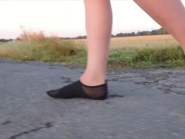 Helle Feinstrumpfhose und Strandschuhe in der Pfütze