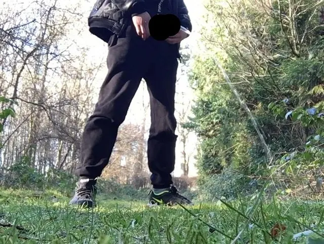boy is urinating in the woods