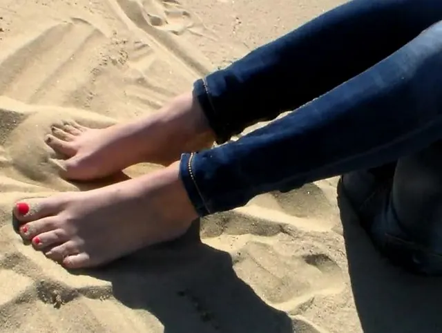 Rot lackierte Zehen im Strandsand